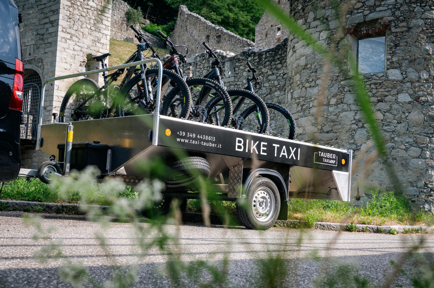 Bike-Taxi-Anhänger mit Mountainbikes vor einer Burgruine